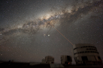 Image of the night sky above Paranal on 21 July 2007, taken by ESO astronomer Yuri Beletsky. A wide band of stars and dust clouds, spanning more than 100 degrees on the sky, is seen. This is the Milky Way, the Galaxy we belong to. At the centre of the image, two bright objects are visible. The brightest is the planet Jupiter, while the other is the star Antares. Three of the four 8.2-m telescopes forming ESO's VLT are seen, with a laser beaming out from Yepun, Unit Telescope number 4. The laser points directly at the Galactic Centre. Also visible are three of the 1.8-m Auxiliary Telescopes used for interferometry. They show small light beams which are diodes located on the domes. The exposure time is 5 minutes and because the tracking was made on the stars, the telescopes are slightly blurred.