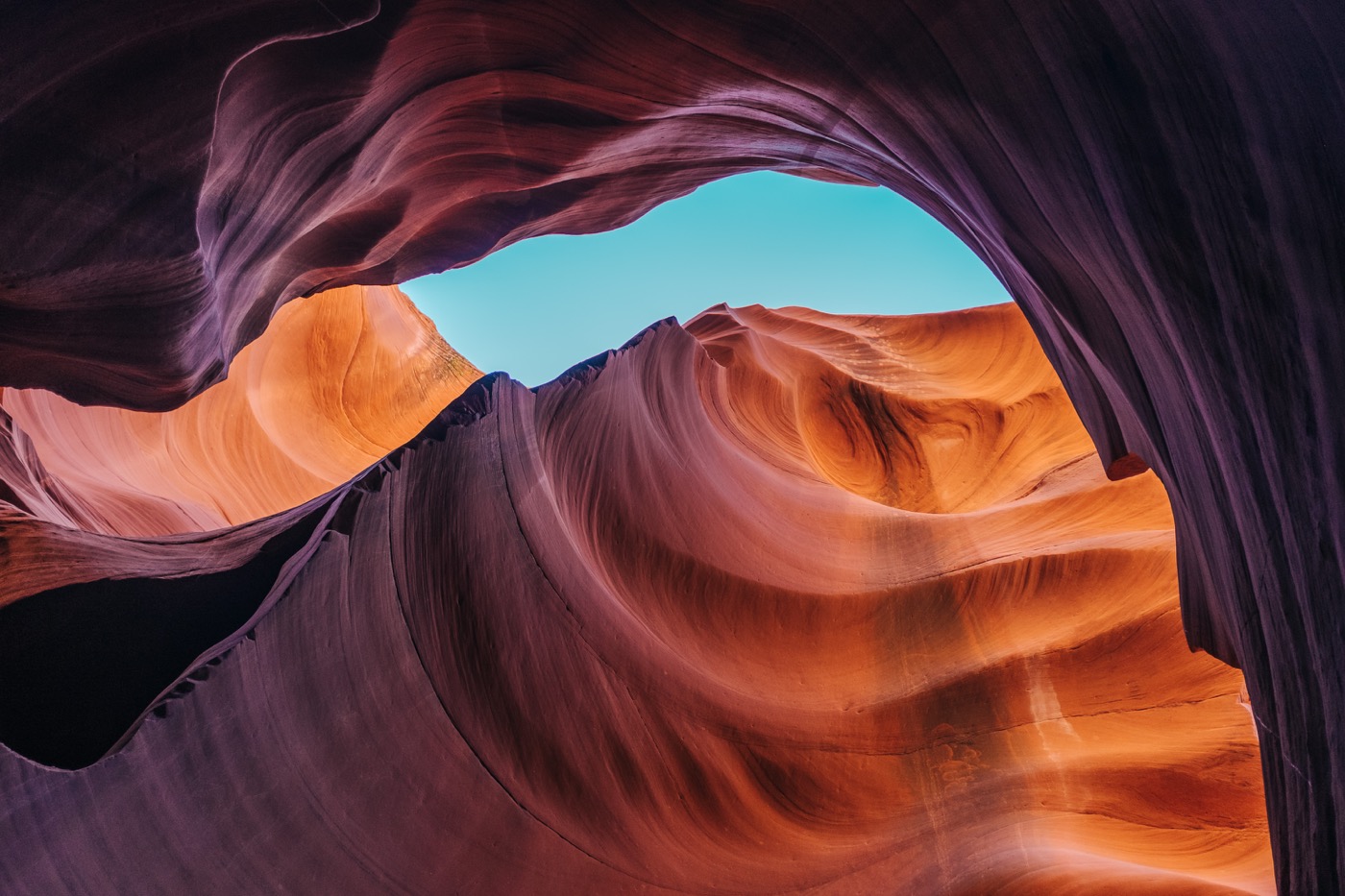 tall and curved canyon walls displaying striations and varied colors as the sun hits