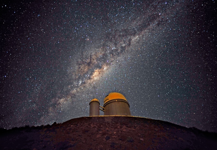 An observatory on a hill with a sky full of stars