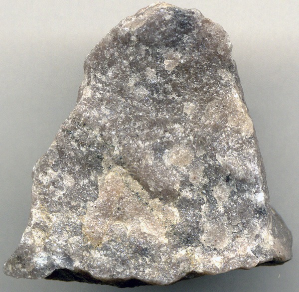 a triangular rock sample, gray, white and yellowish in color