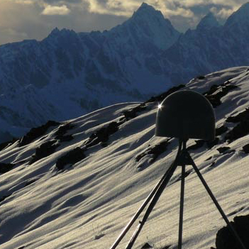 GPS monitor on a stand sitting on top of a mountain, overlooking another range of mountains