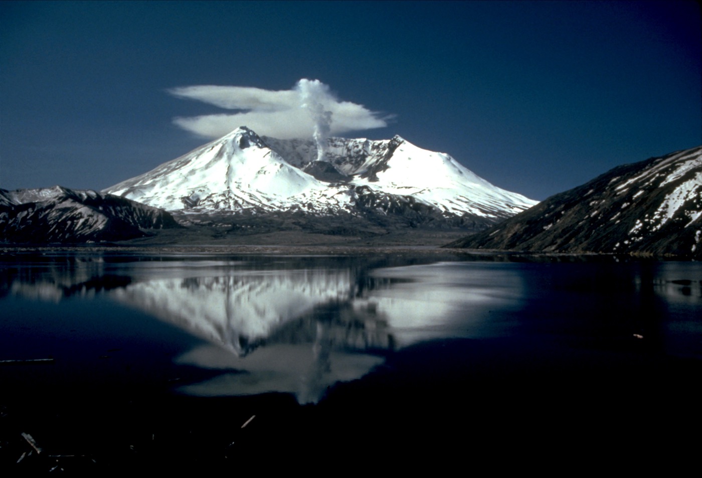 The crater of Mt. St. Helens with a plume of smoke escaping.