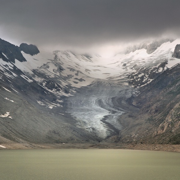 A glacier in the middle of a valley on a cloudy day