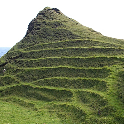 A small grassy hill with terraces horizontally stepping from top to bottom