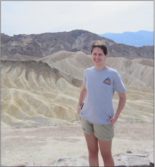Professor Emily Haddad stands in front of a desert landform.