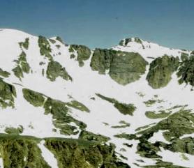 A deep, bowl-shaped rocky depression carved into a mountain ridge above a valley.