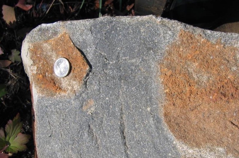 Chemically weathered surface (red-brown) of an igneous diabase (mafic, shallow intrusive) from Virginia. The chipped surface (black) shows the original color of the unweathered diabase. Credit: Callan Bentley