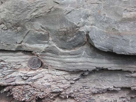 Animated GIF showing an annotated view of a photograph of ball & pillow and flame structures, developed together along a sand/mud interface in sedimentary strata. A quarter serves as a sense of scale.