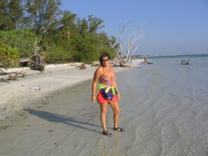 Colleen Chamberlin on a white Sanibel Island sand beach bordered by coastal pines and seagrapes.