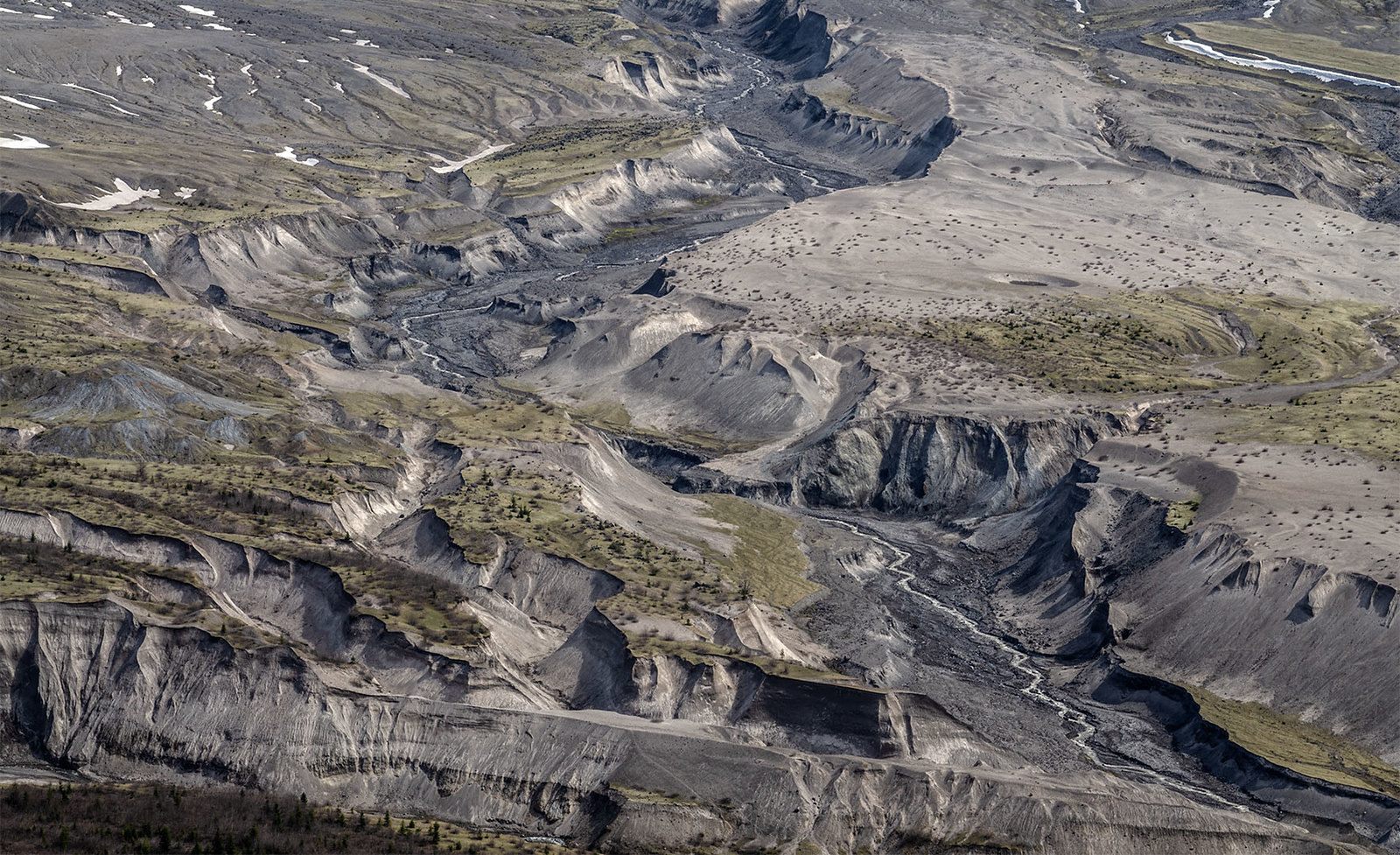 Ash landscape with streams carving U-shaped canyons through it.