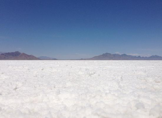 Photo of white salt crust at the Bonneville Salt Flats in Utah with mountains in the background.