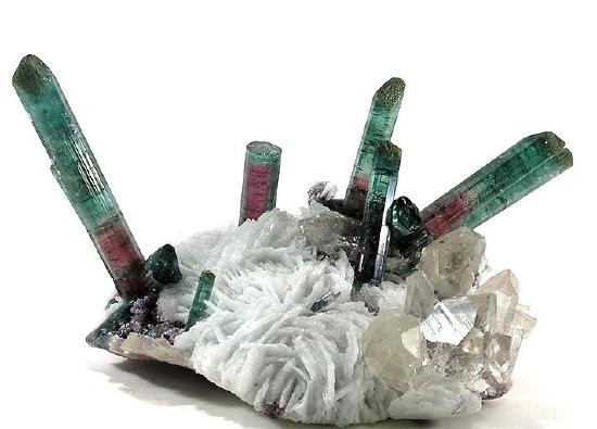 Long cylindrical crystals of tourmaline that are purple turning to green coming out of a white rock.