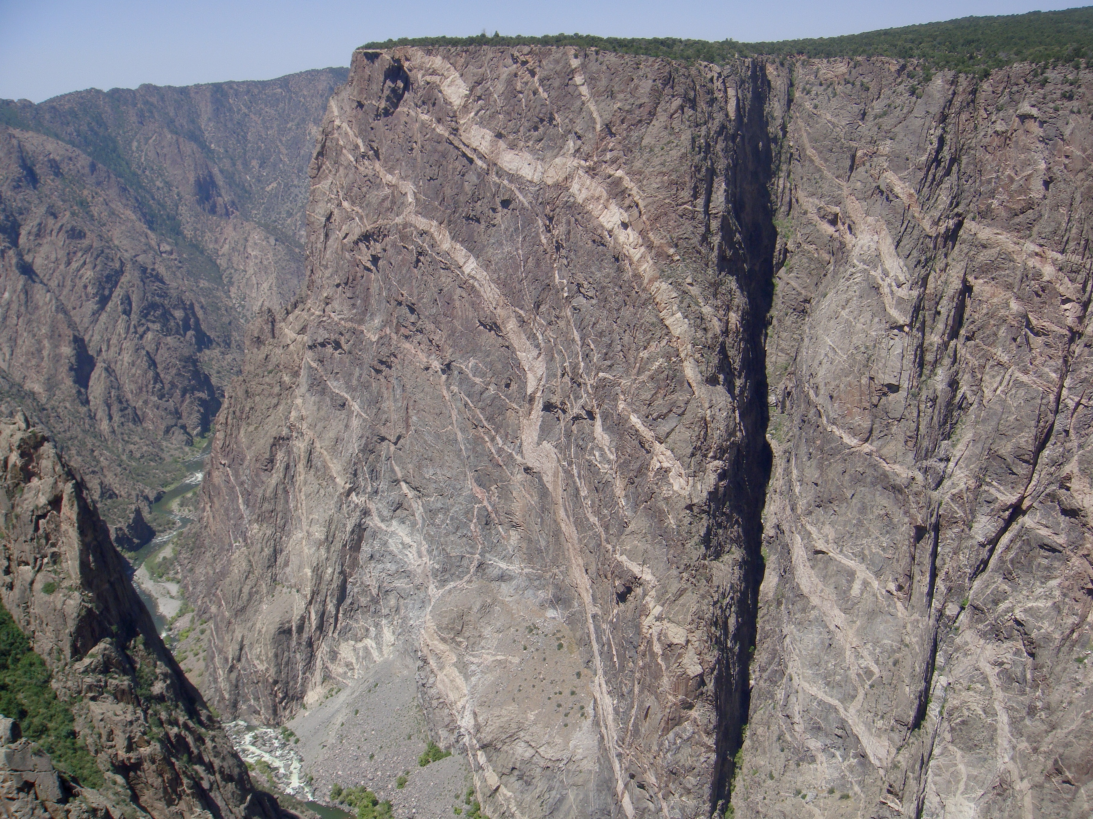 The wall is a large cliff of dark gray rock with marbled white veins running from upper left to lower right.