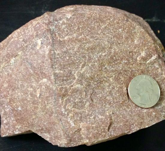 Dull pink rock with fused quartz grains. 