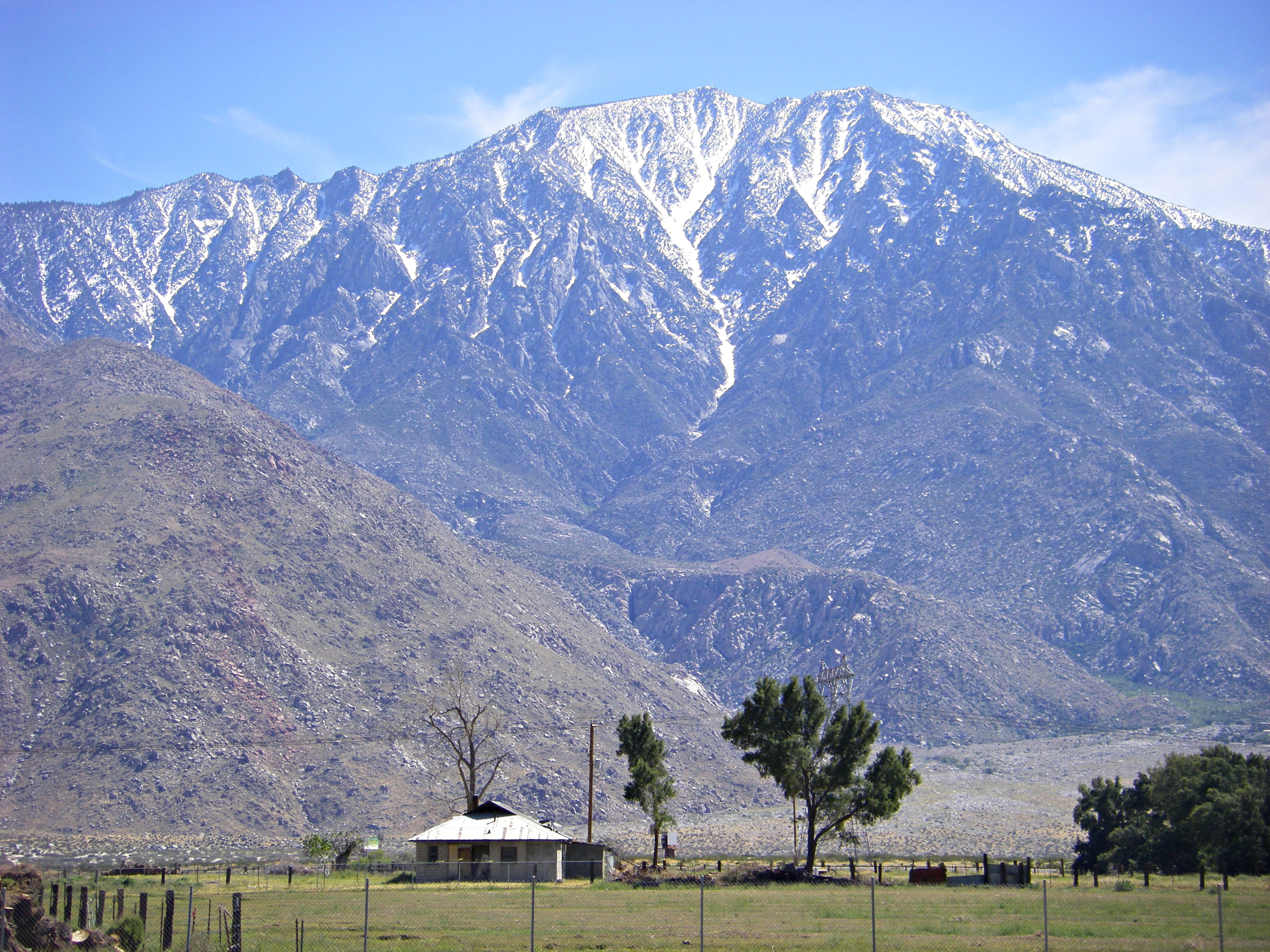 Abandoned farm with large, snow dusted mountain in the background.