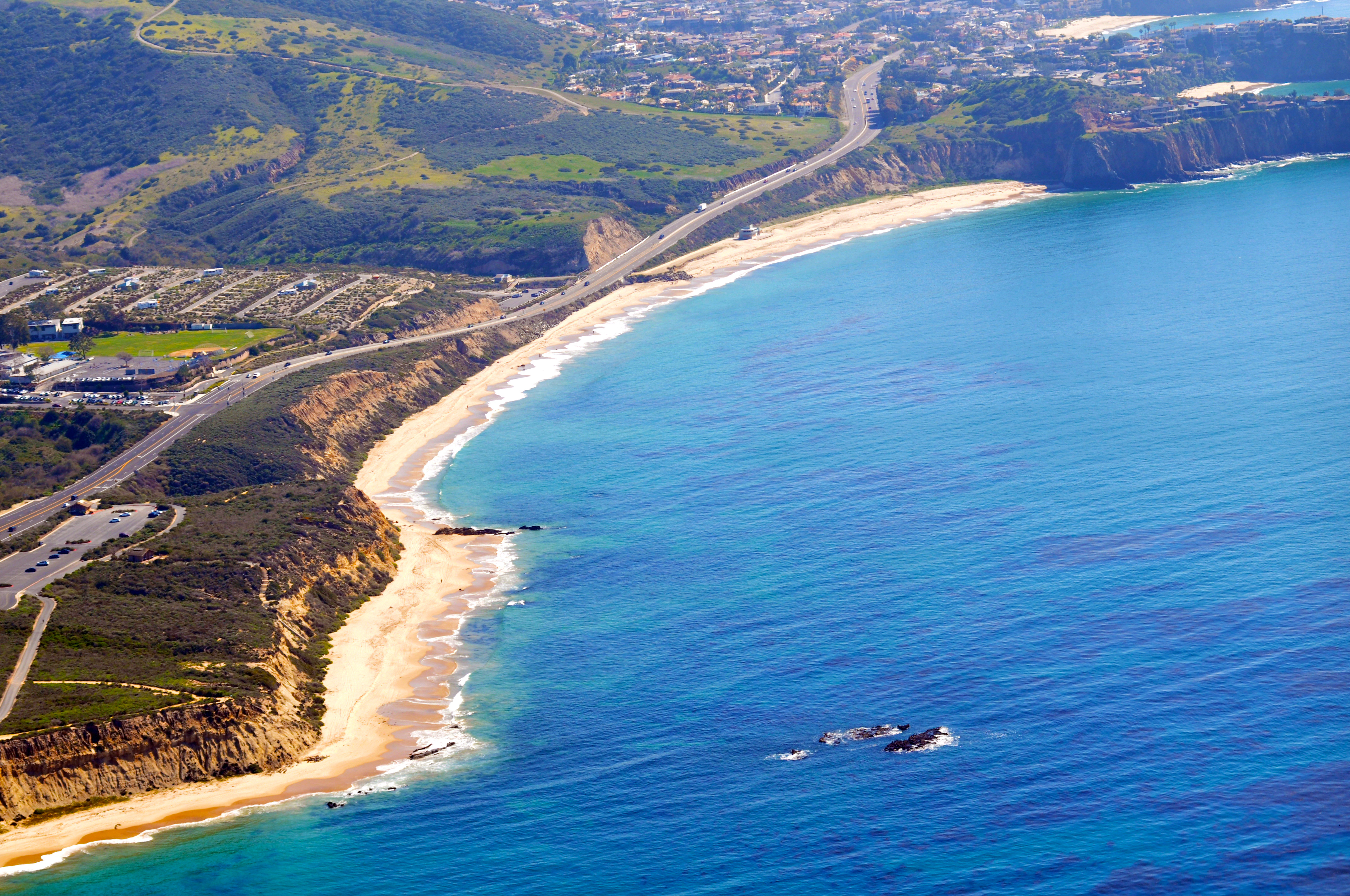A highway crossing between subdivisions on top of the marine terraces with beaches and the ocean off to the west.