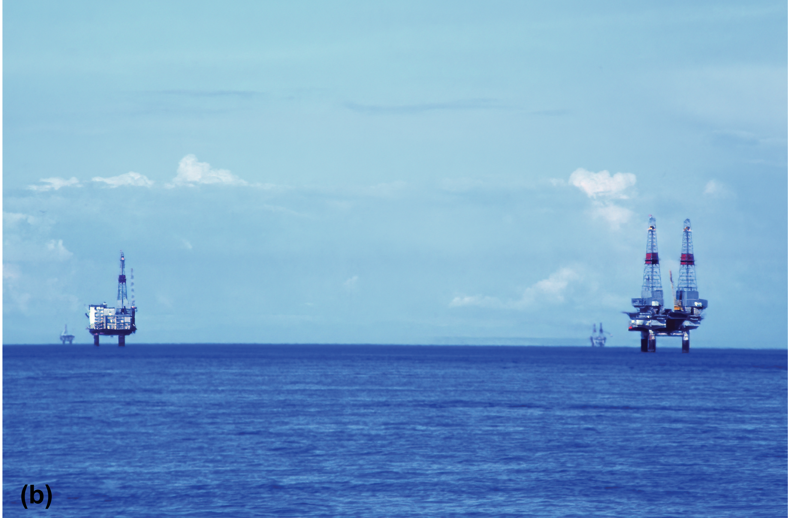 Two distant oil rigs with a third one in the distance