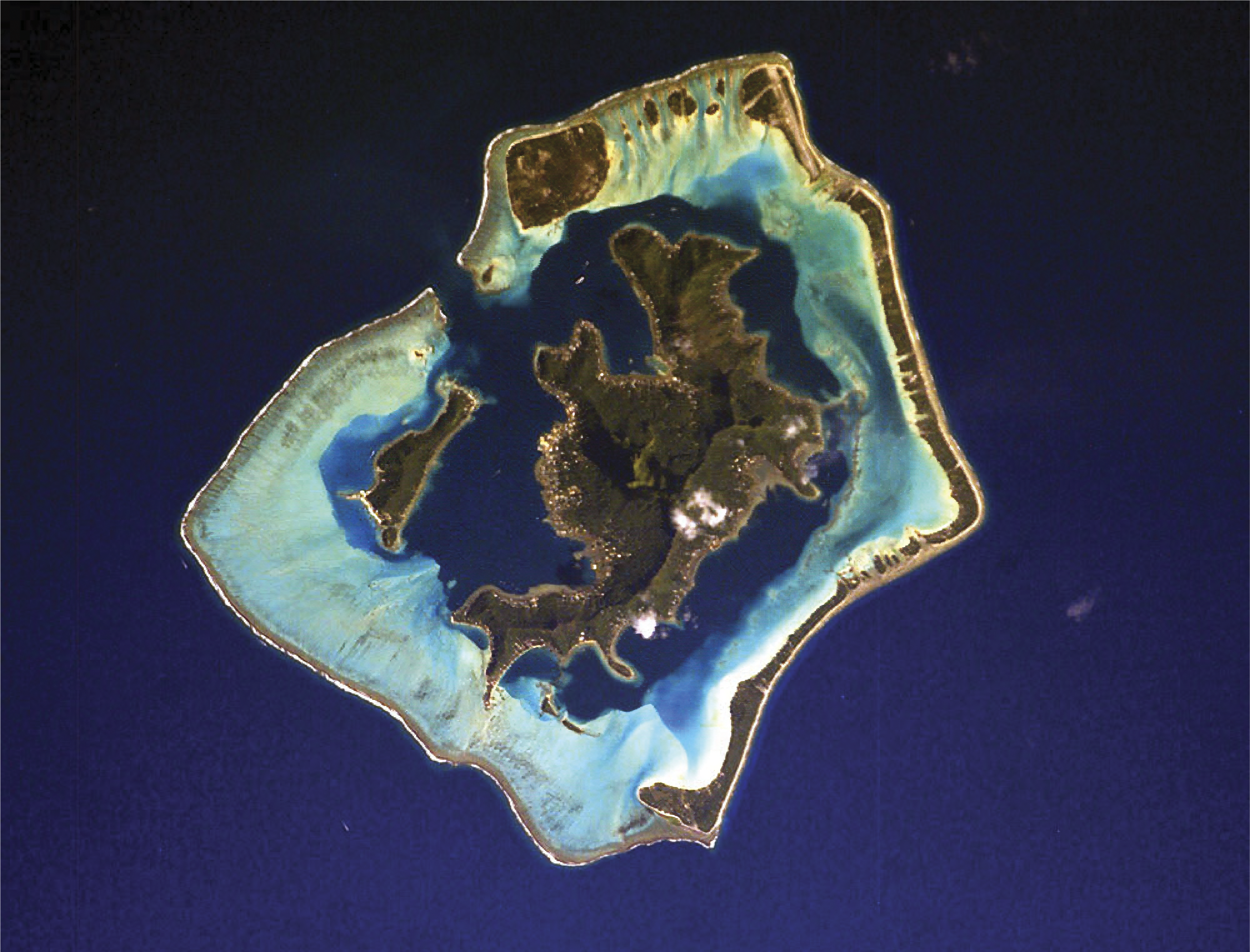 An irregularly shaped island surrounded by an angular area of sand bars and thin spits of land