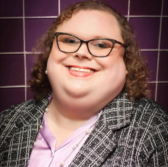 Alicia wearing a formal jacket and smiling at the camera