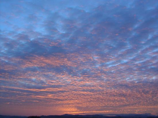 Darker clouds reflecting the red setting sunlight and turning red.