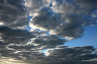 Flat clumps of darker clouds with some blue skies in the middle.
