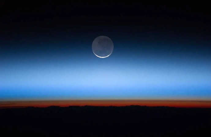 Earth&rsquo;s horizon from the ISS showing distinct atmospheric layers, including the orange-red troposphere.