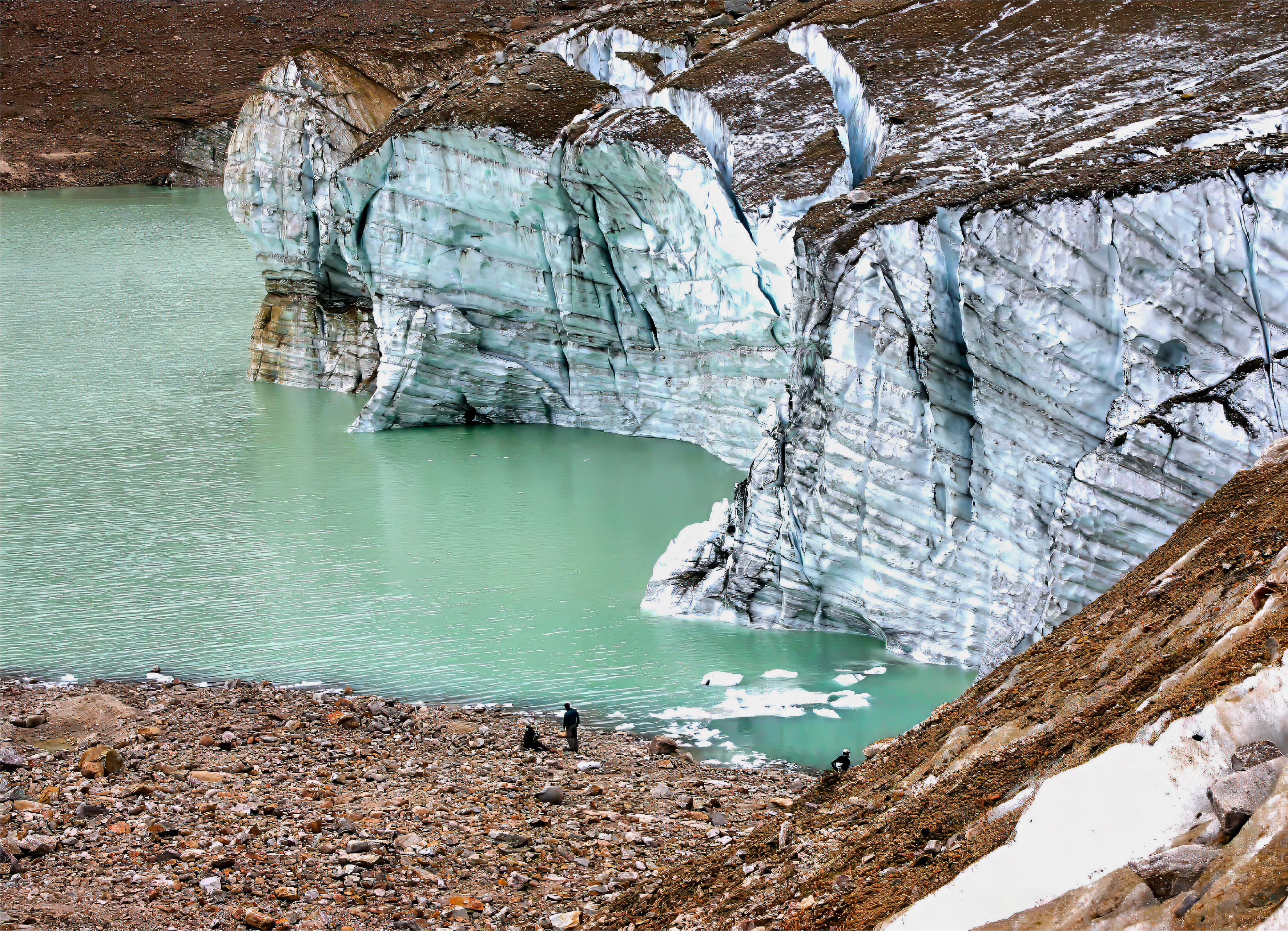 Milky greenblue lake beside a glacier and next to a rocky beach