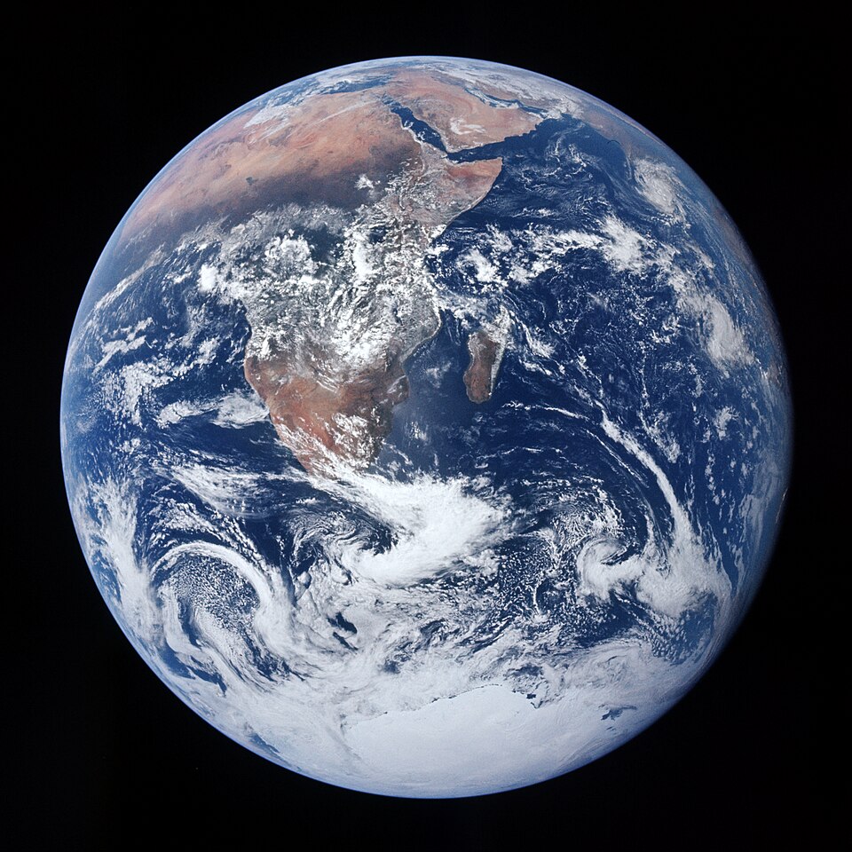 A photograph of Earth from space showing a blue sphere with some land, forests, grasslands, oceans and clouds.