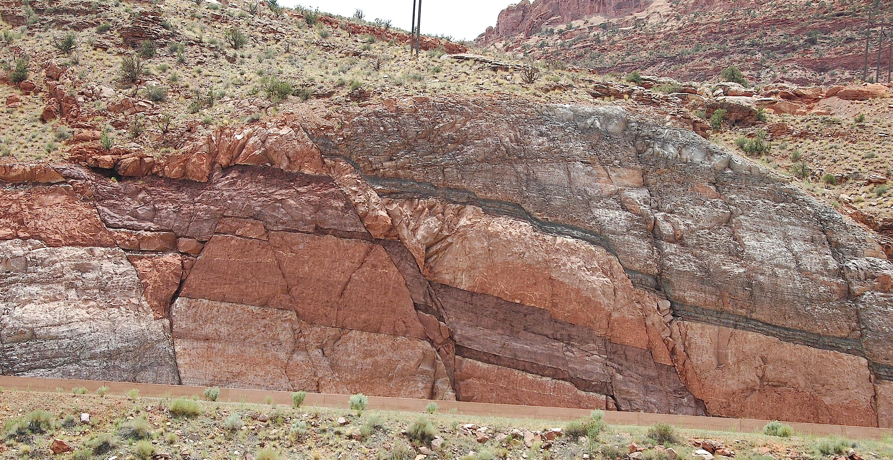 Roadcut outcrop of multicolor rock beds offset by a normal fault.
