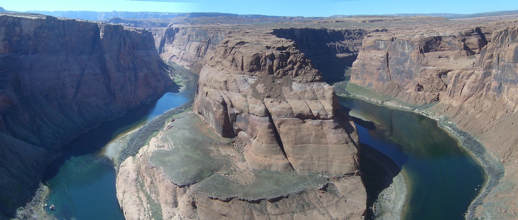 Entrenched meander of the Colorado River, downstream of Page, Arizona. High cliffs, that lead down to a river with narrow shores.