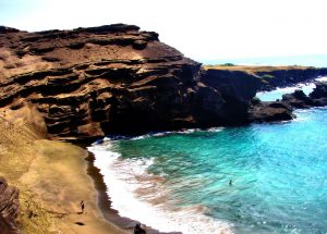 Playa hawiiana compuesta de arena verde olivina de la intemperie de la roca basáltica cercana.