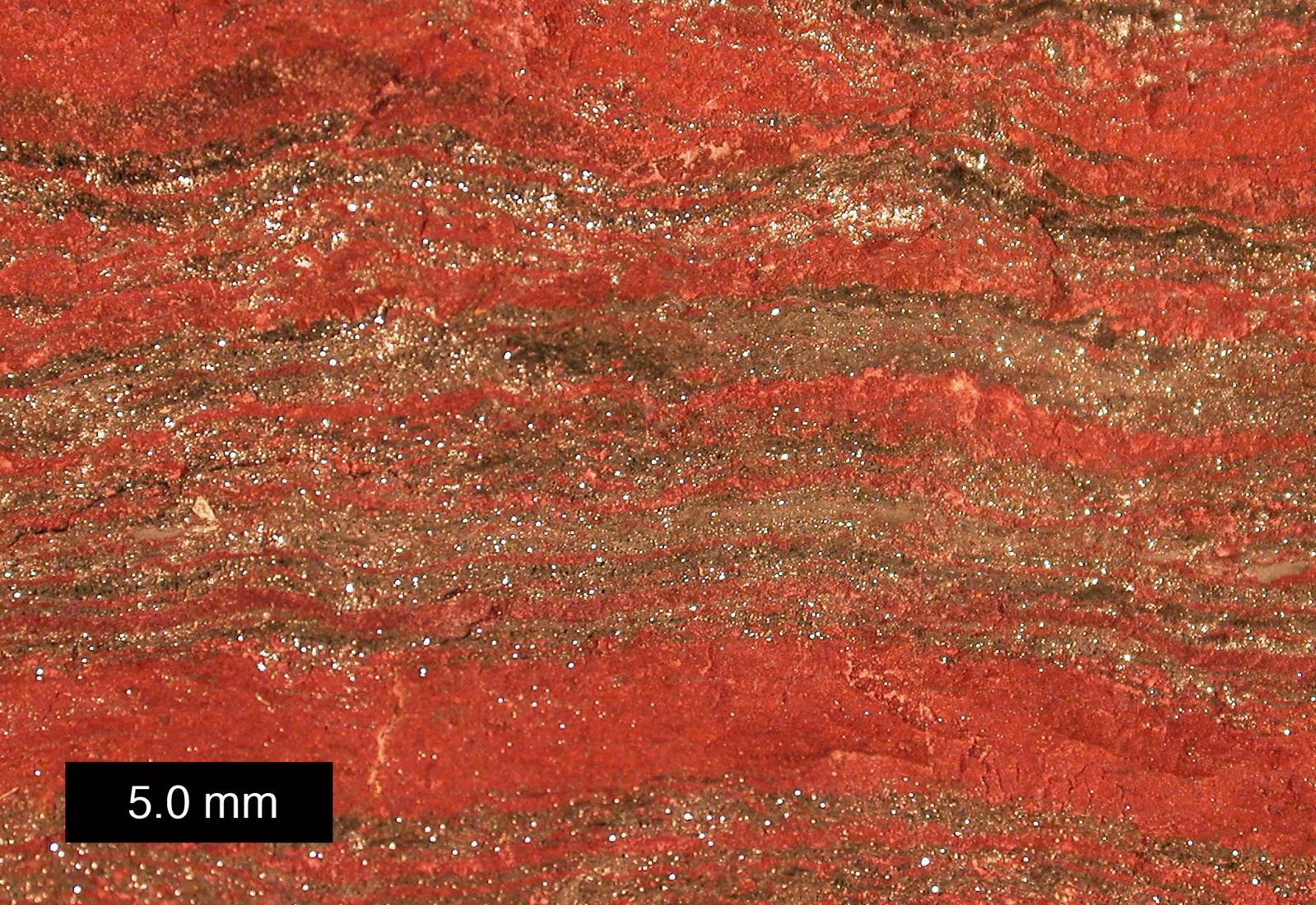 La roca muestra capas rojas y marrones.