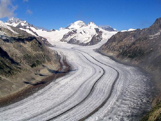 Glacier in the Bernese Alps. A thick sheet of ice filling an alpine valley with lines of sediment (medial moraine).