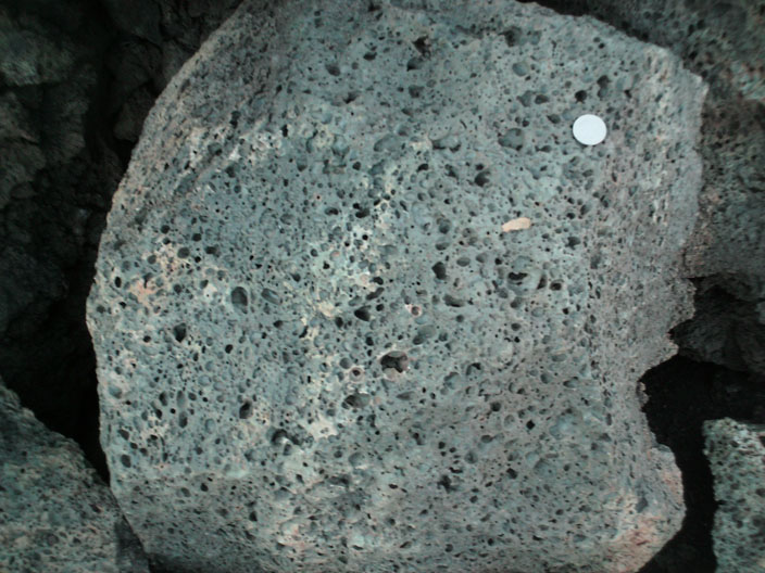 Dark grey rock with many visible holes and no visible crystals.