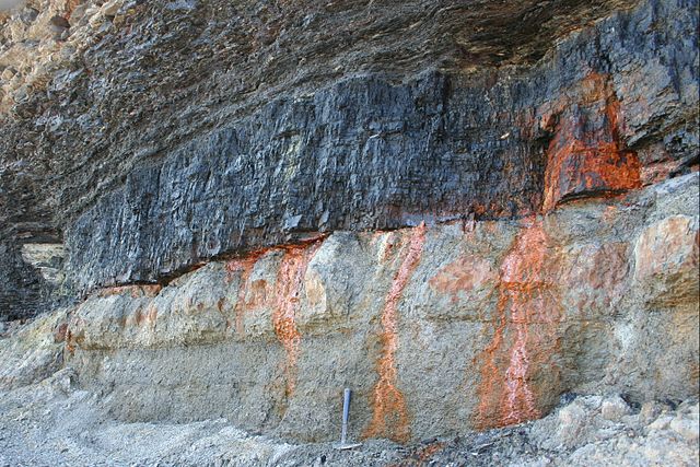 A rock cliffside with orange streaks running through it